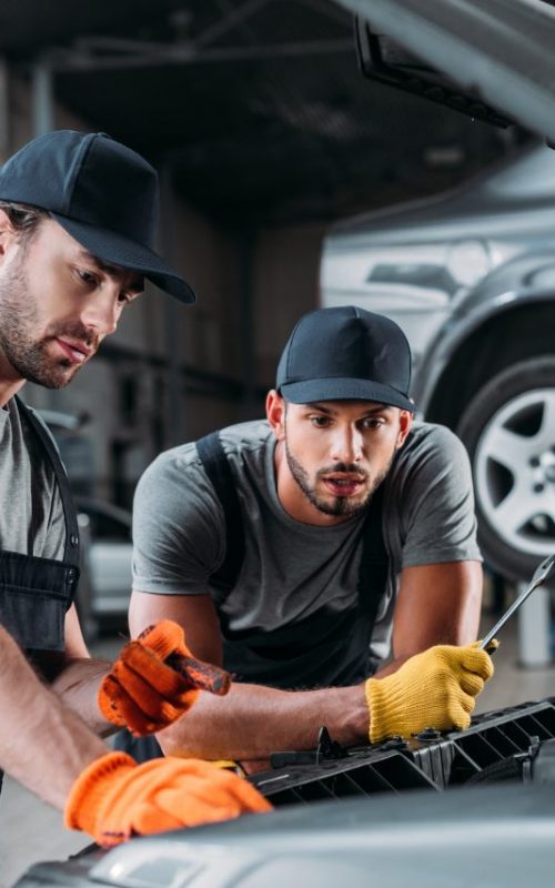 professional-manual-workers-repairing-car-in-mechanic-shop